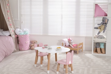 Photo of Cute child's room interior with toys and modern furniture