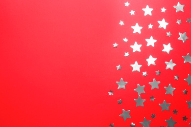 Confetti stars with space for text on red background, flat lay. Christmas celebration