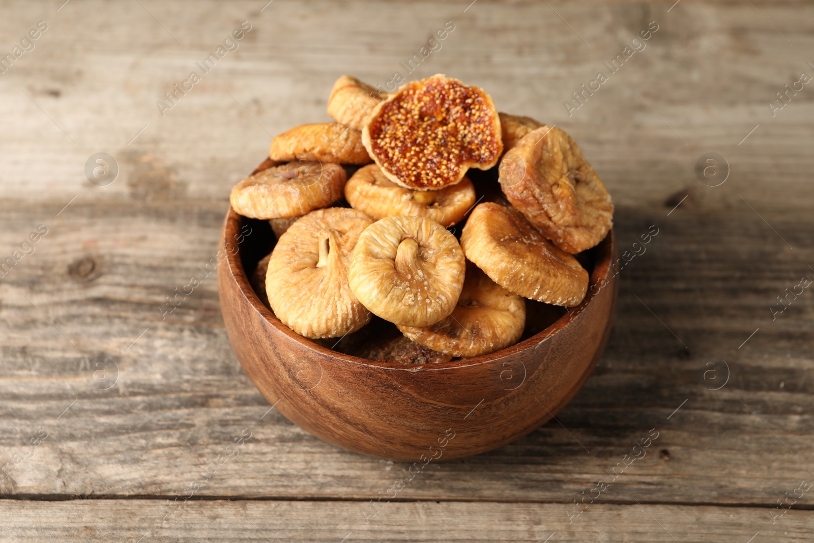 Photo of Bowl with tasty dried figs on wooden table