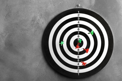 Arrows hitting dart board on grey wall. Space for text