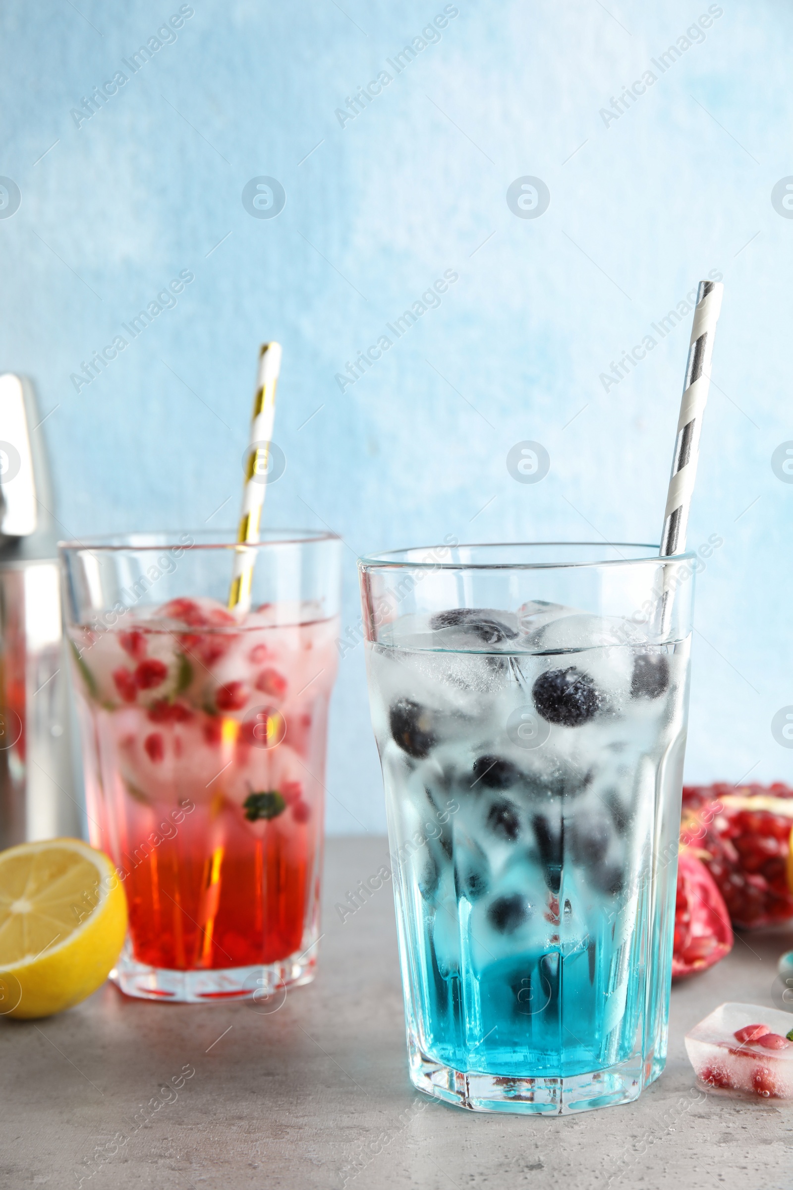 Photo of Tasty cocktails with fruit ice cubes on table against color background. Space for text