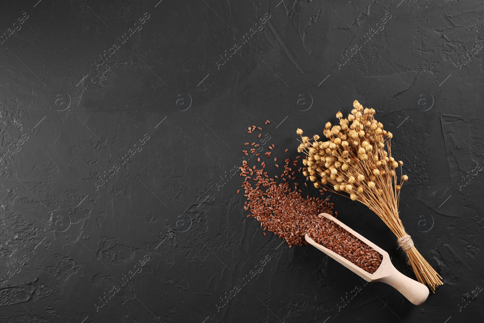 Photo of Flax seeds and dry flowers on grey textured table, flat lay. Space for text