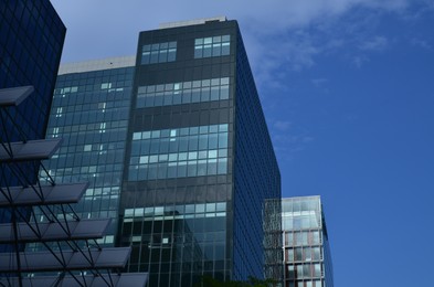 Exterior of beautiful modern skyscraper against blue sky, low angle view