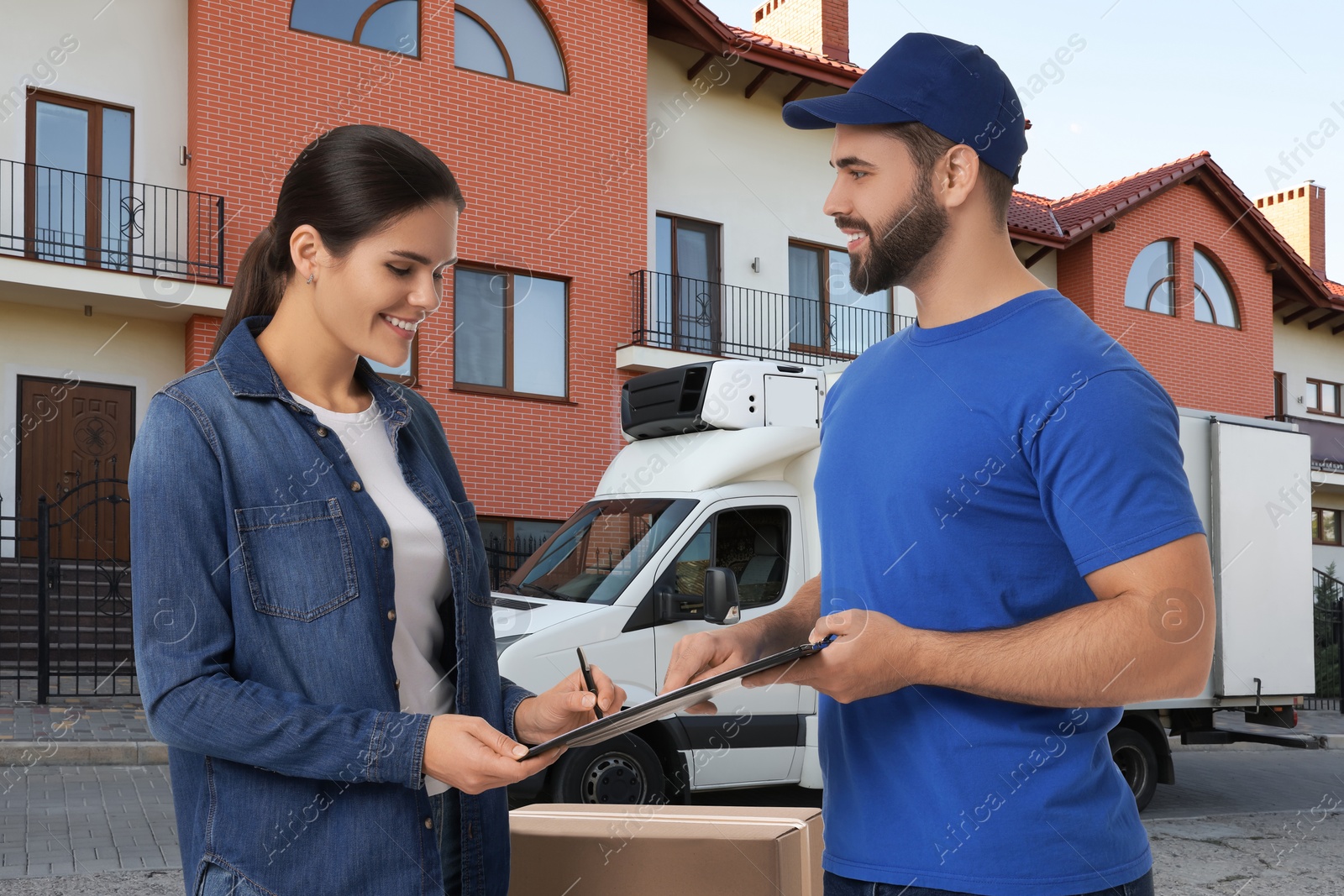 Image of Courier delivery. Woman signing order receipt outdoors