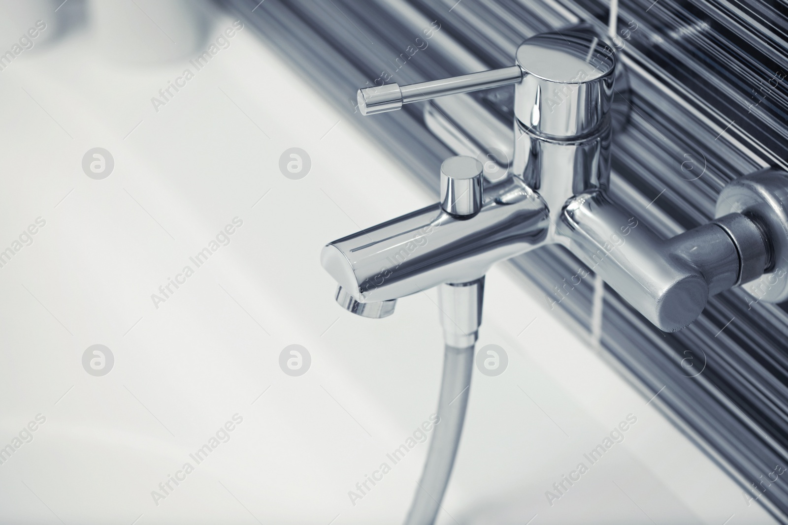 Photo of Shiny water tap installed on black and white wall above bathtub