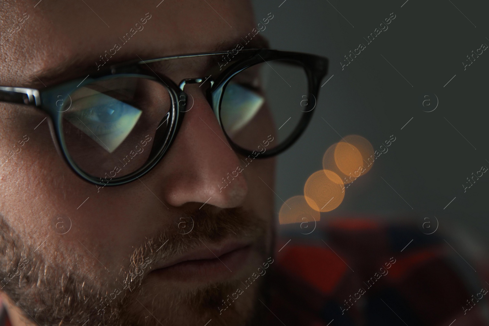 Photo of Young man wearing glasses on blurred background, closeup. Ophthalmology service