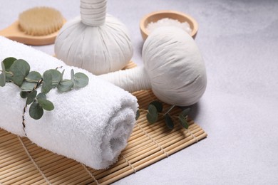 Photo of Spa composition with herbal massage bags and eucalyptus branches on grey table. Space for text