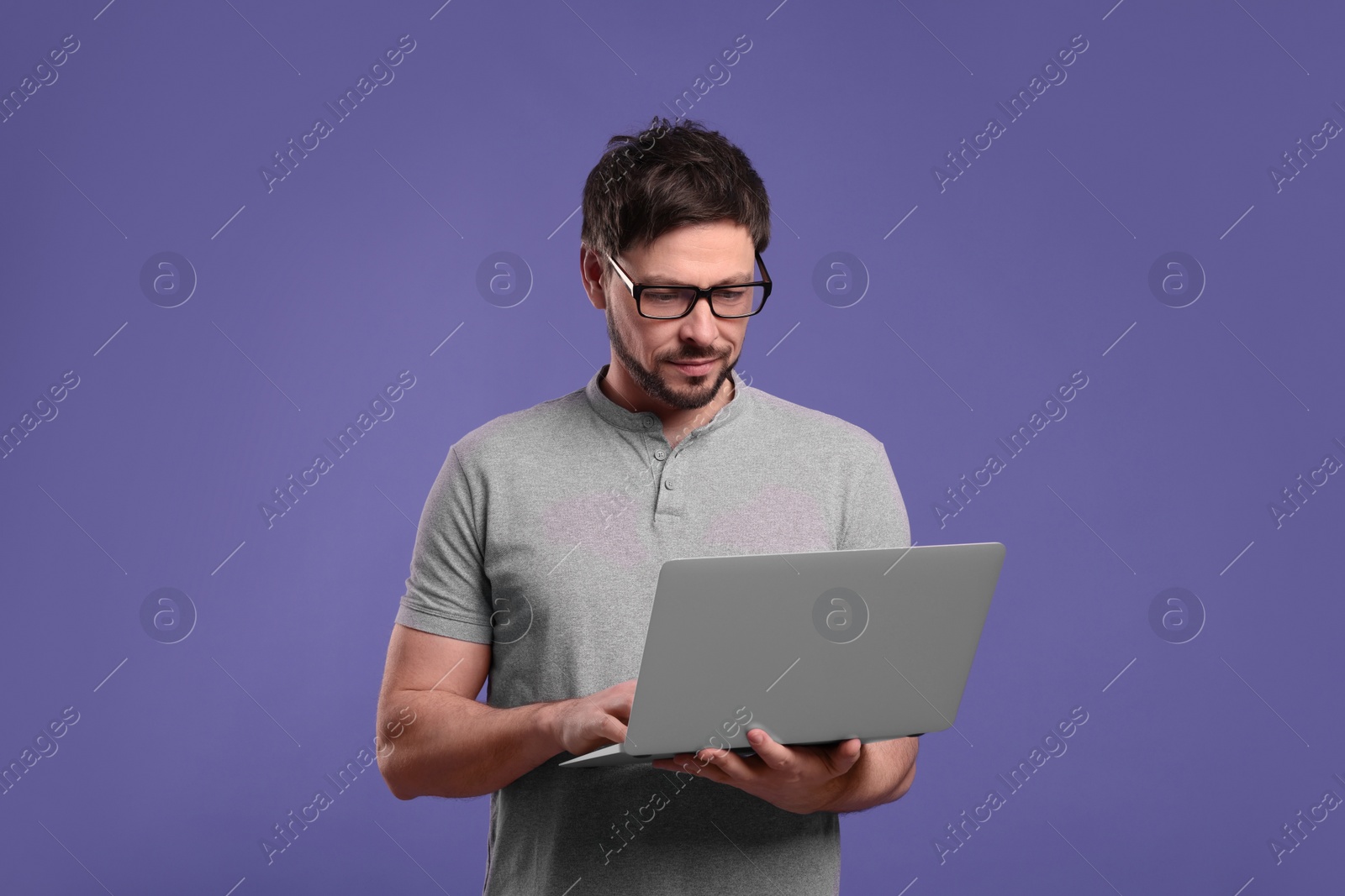 Photo of Handsome man with laptop on lilac background