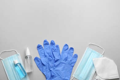 Photo of Flat lay composition with medical gloves, masks and hand sanitizers on grey background. Space for text