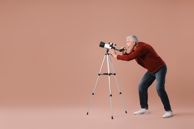 Photo of Senior astronomer with telescope on brown background. Space for text