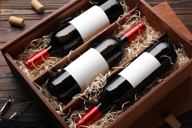 Photo of Box with wine bottles on wooden table, above view