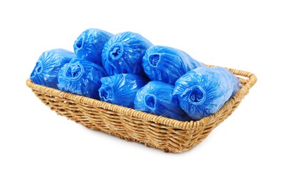 Photo of Rolled blue shoe covers in wicker basket isolated on white