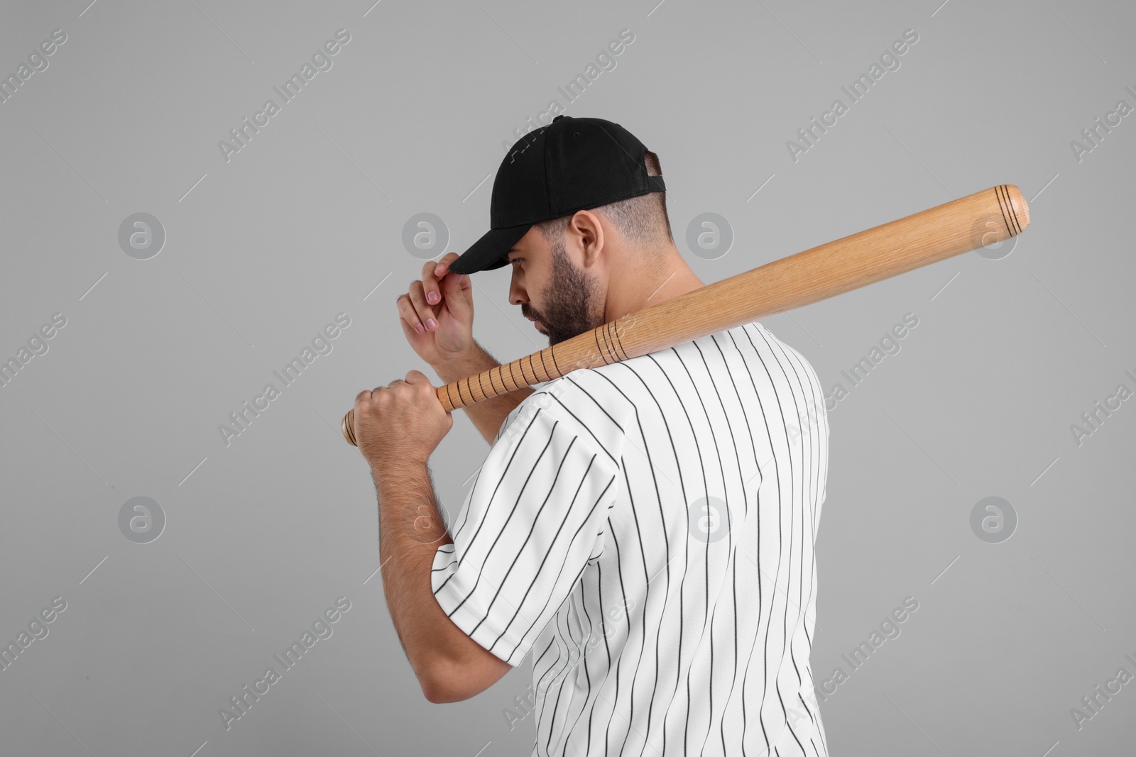 Photo of Man in stylish black baseball cap holding bat on light grey background