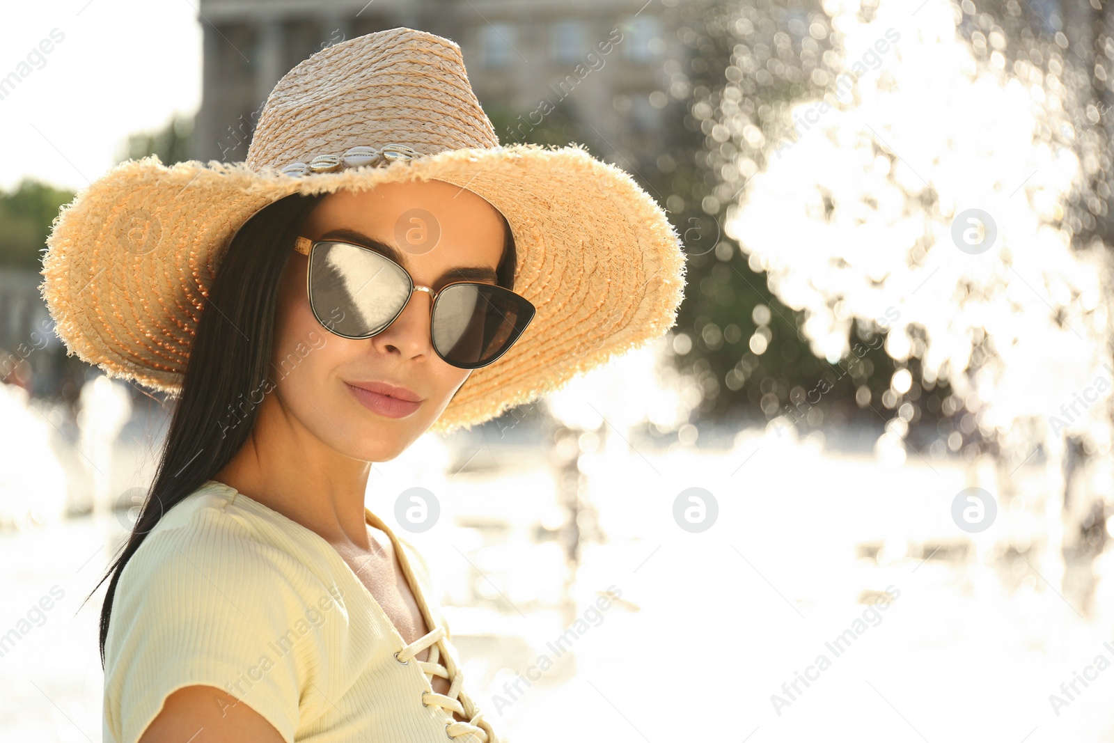 Photo of Beautiful young woman wearing stylish sunglasses outdoors. Space for text