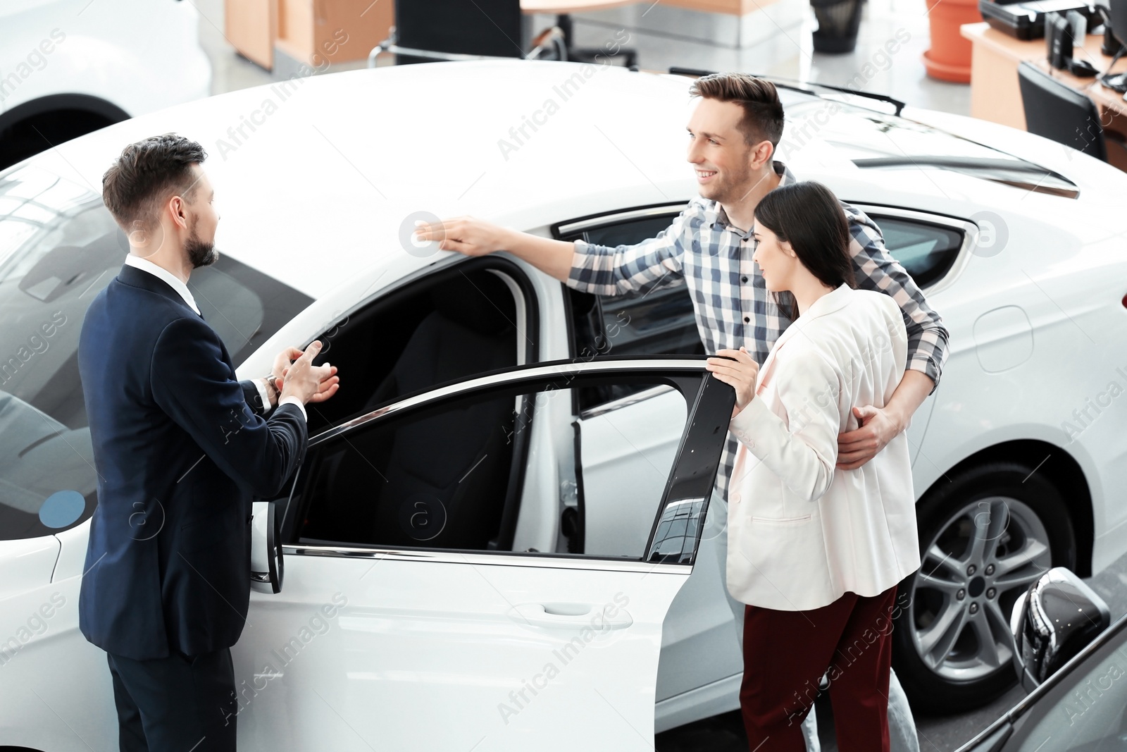 Photo of Young couple buying new car in salon