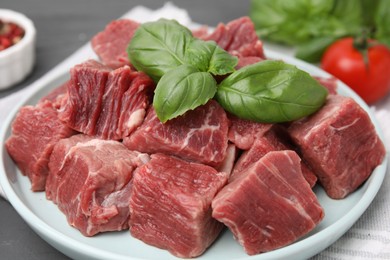 Photo of Cut fresh beef meat with basil leaves on table, closeup