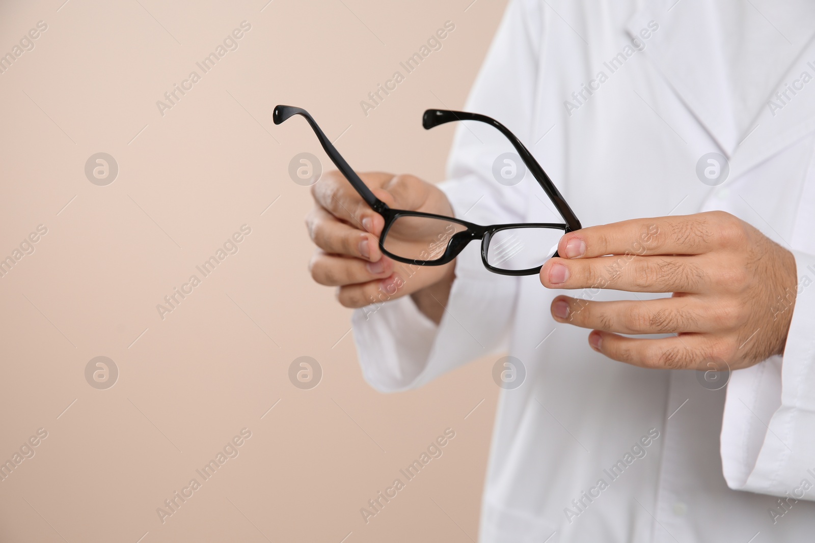 Photo of Male ophthalmologist with eyeglasses on light background, closeup. Space for text
