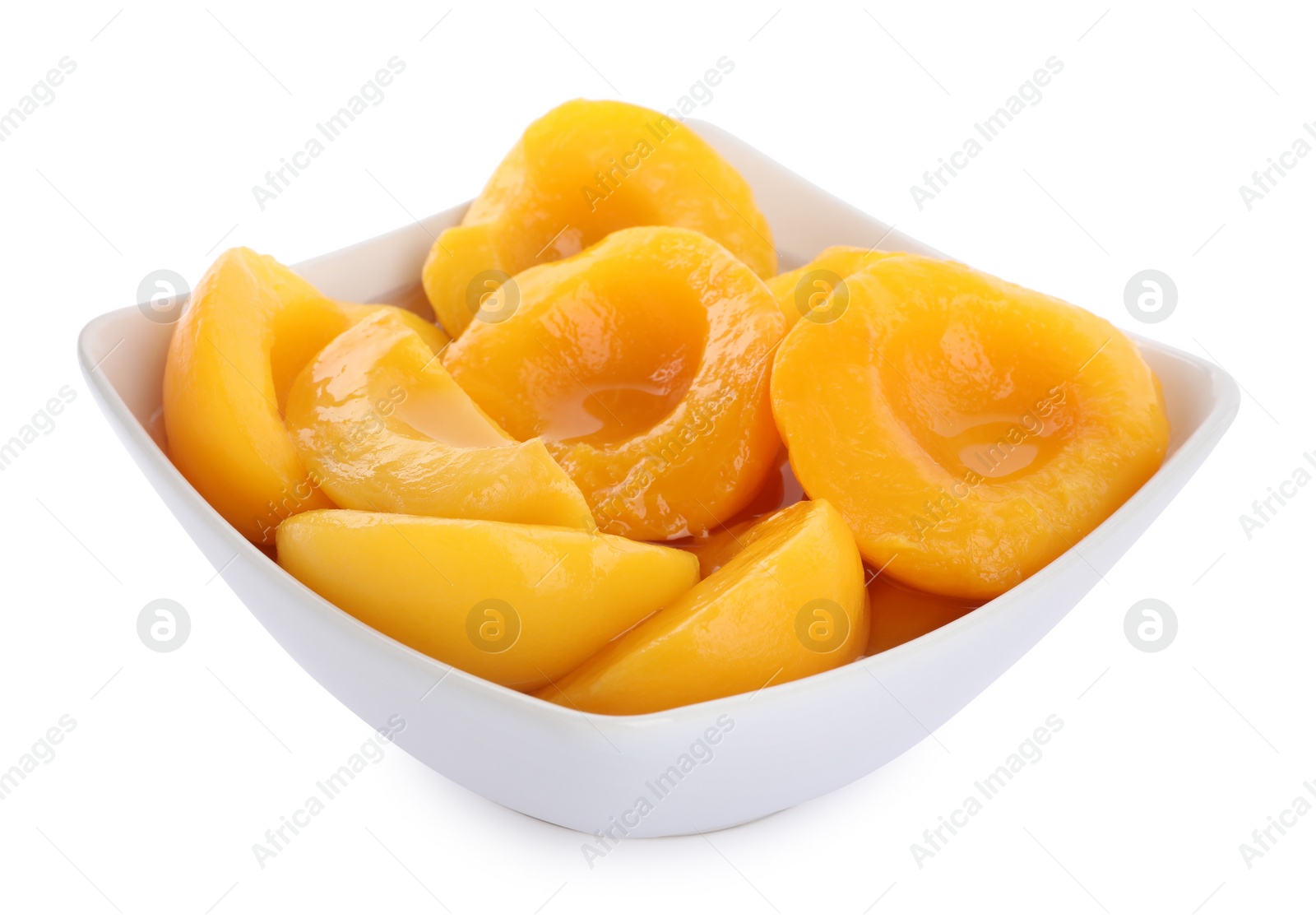 Photo of Halves of canned peaches in bowl isolated on white