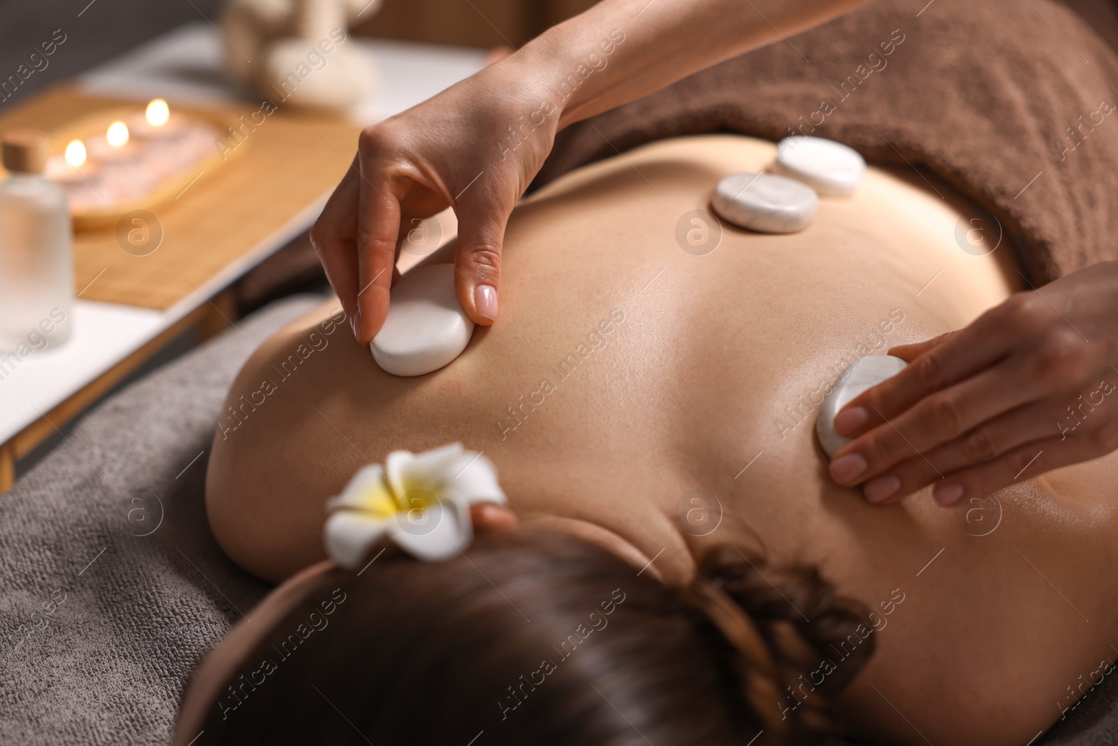 Photo of Spa therapy. Beautiful young woman lying on table during hot stone massage in salon, closeup