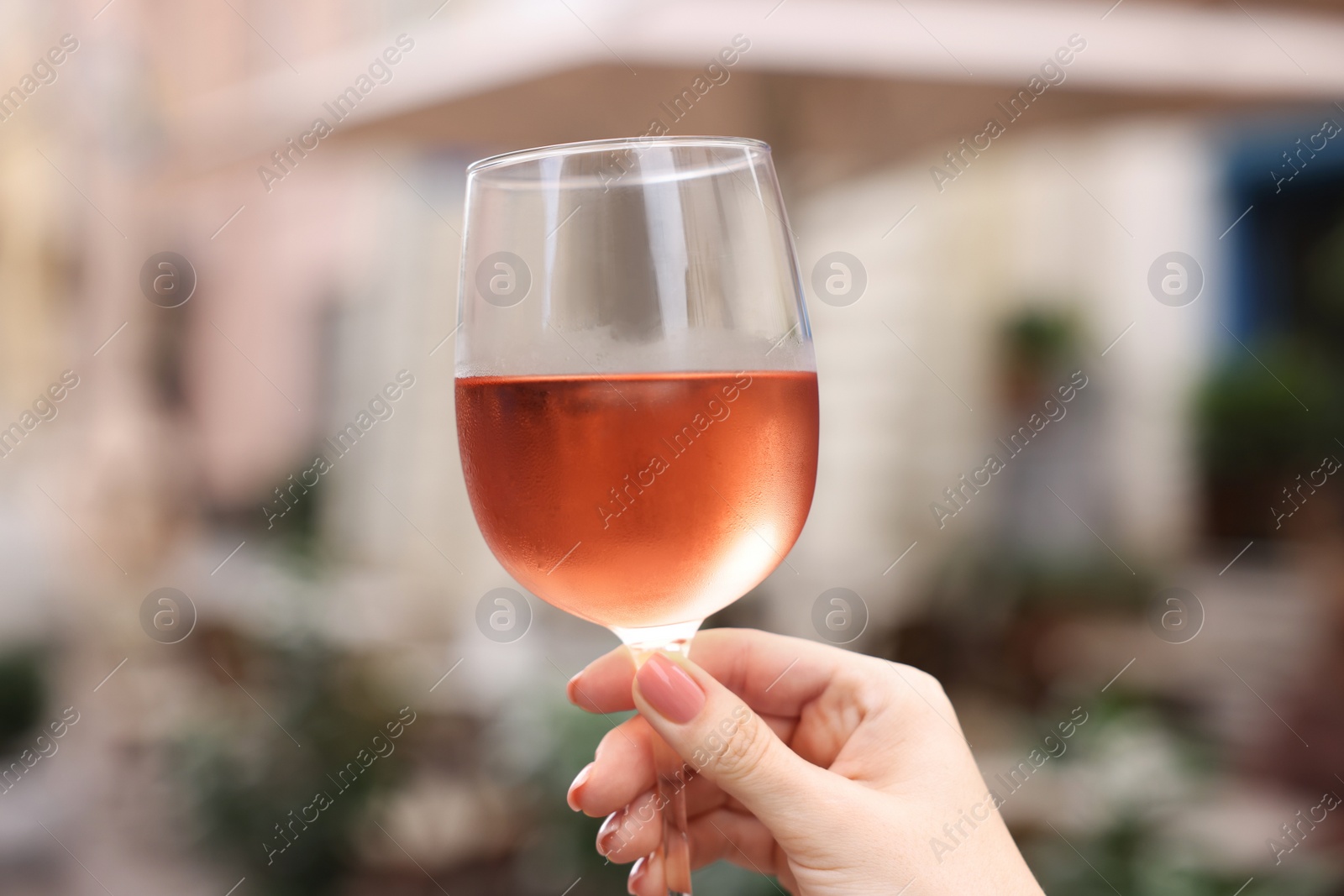 Photo of Woman holding glass of rose wine outdoors, closeup