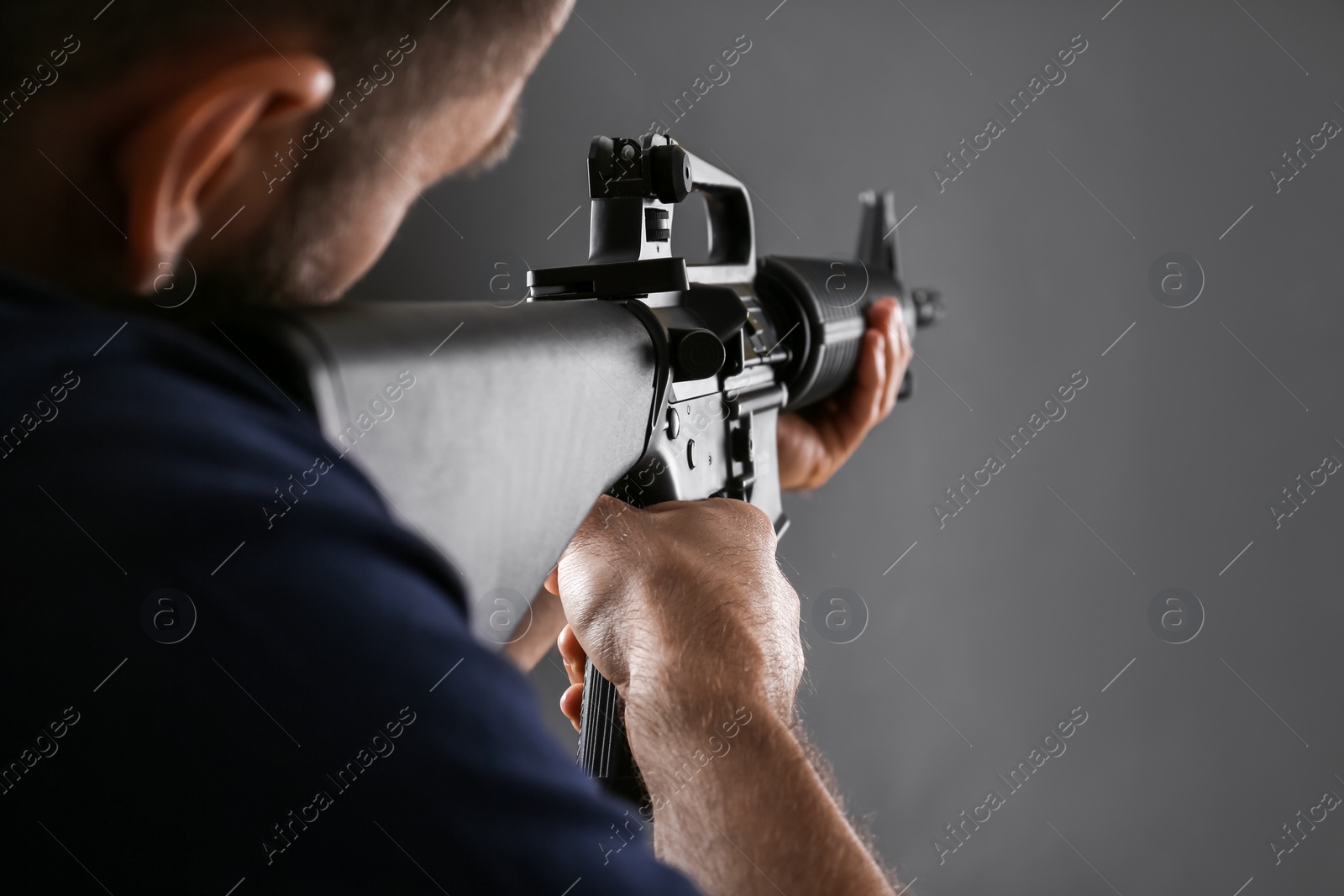 Photo of Assault gun. Man aiming rifle on dark background, closeup
