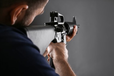 Assault gun. Man aiming rifle on dark background, closeup