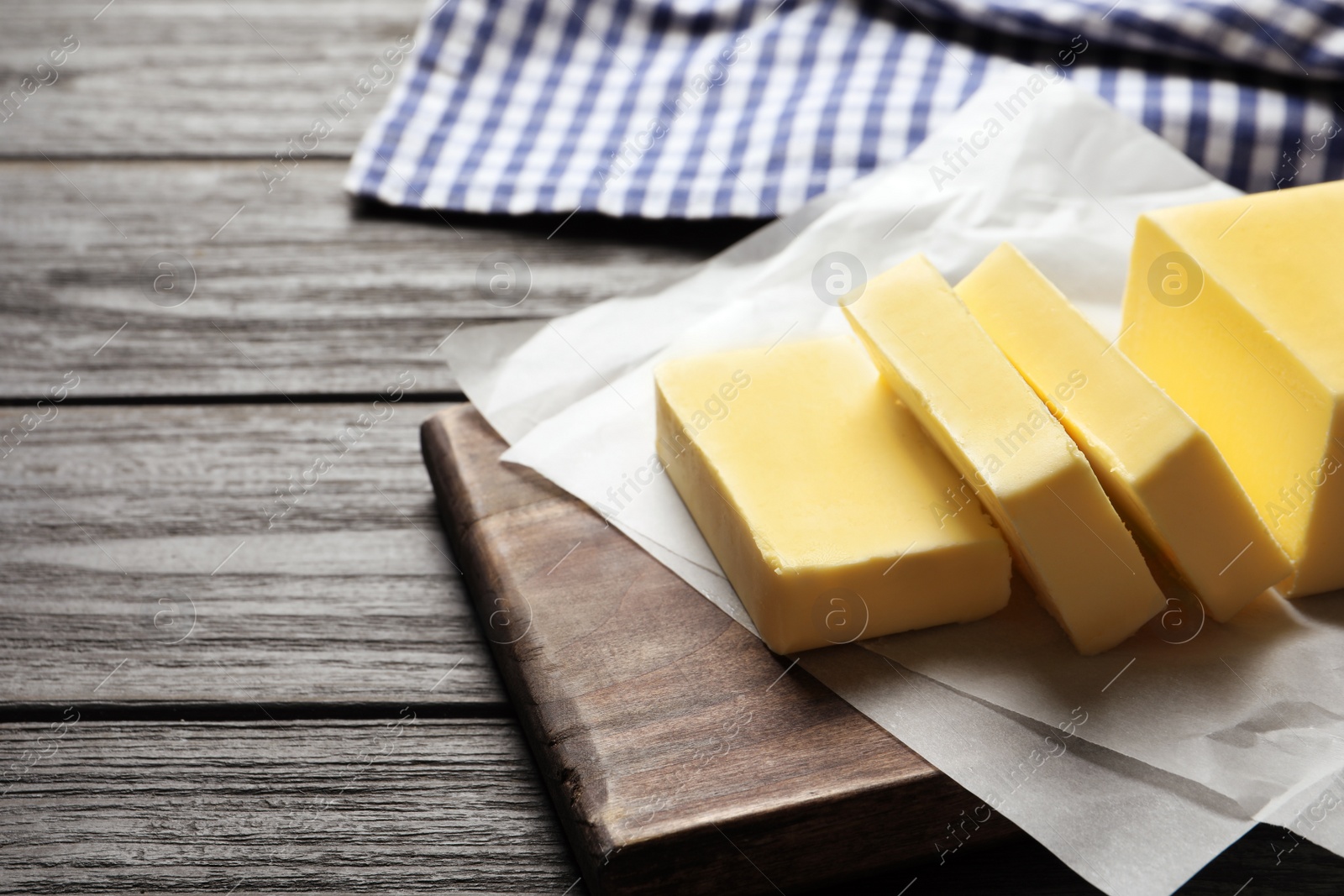 Photo of Wooden board with fresh butter on table. Space for text