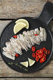 Photo of Tasty anchovies with spices and lemon slices on wooden table, top view