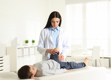 Professional orthopedist examining little patient's leg in clinic