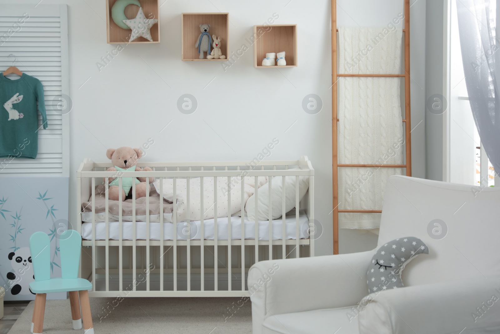 Photo of Stylish baby room interior with crib and armchair