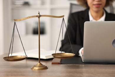 Photo of Notary using laptop at workplace in office, focus on scales of justice