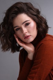 Photo of Portrait of beautiful young woman with wavy hairstyle on grey background