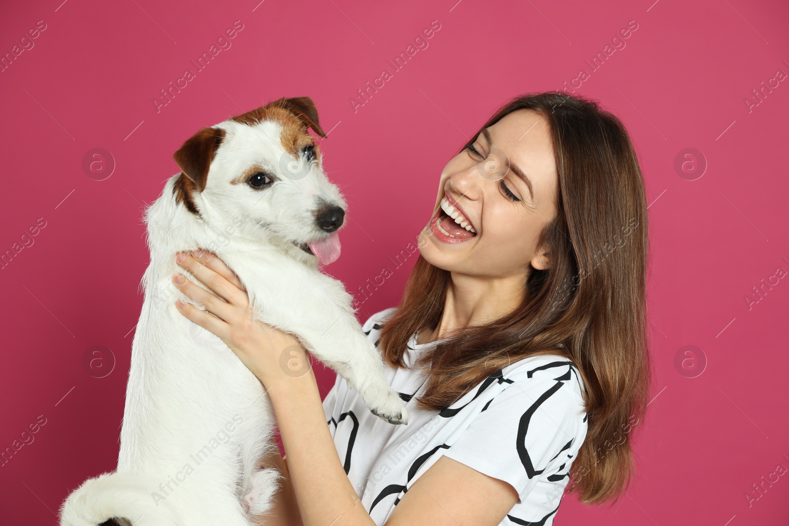 Photo of Young woman with her cute Jack Russell Terrier on pink background. Lovely pet