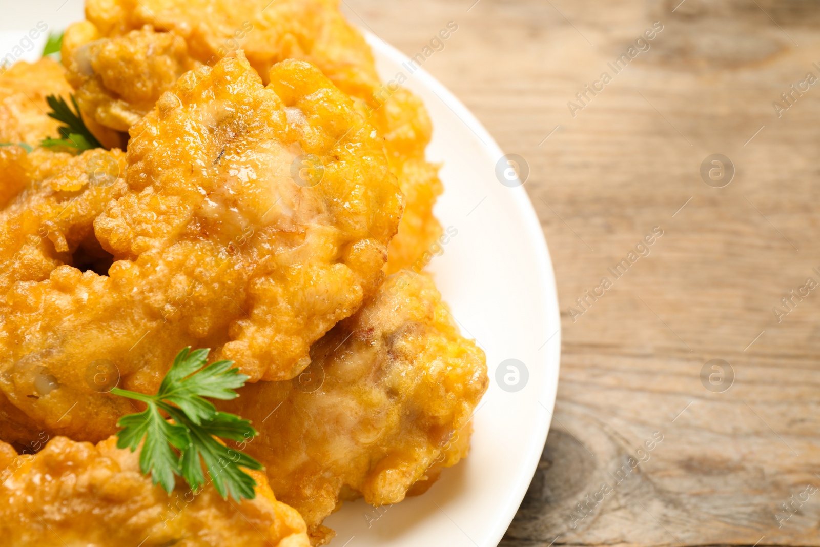 Photo of Tasty deep fried chicken pieces served on wooden table, closeup