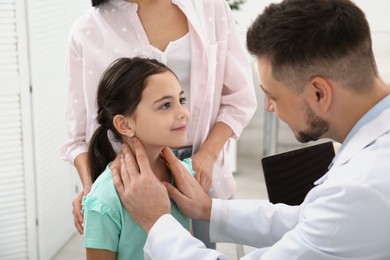 Mother with daughter visiting pediatrician in hospital. Doctor examining little girl