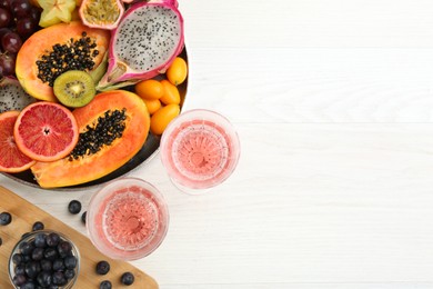 Photo of Delicious exotic fruits and wine on white wooden table, flat lay. Space for text