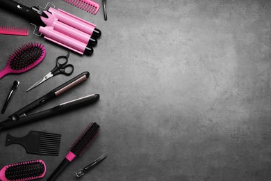 Flat lay composition of professional hairdresser tools on dark grey table, space for text