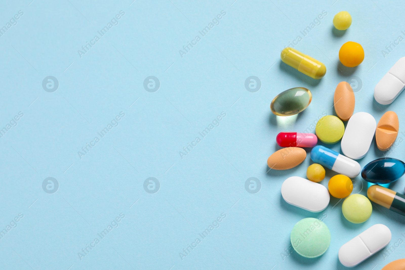 Photo of Many different pills on light blue background, flat lay. Space for text