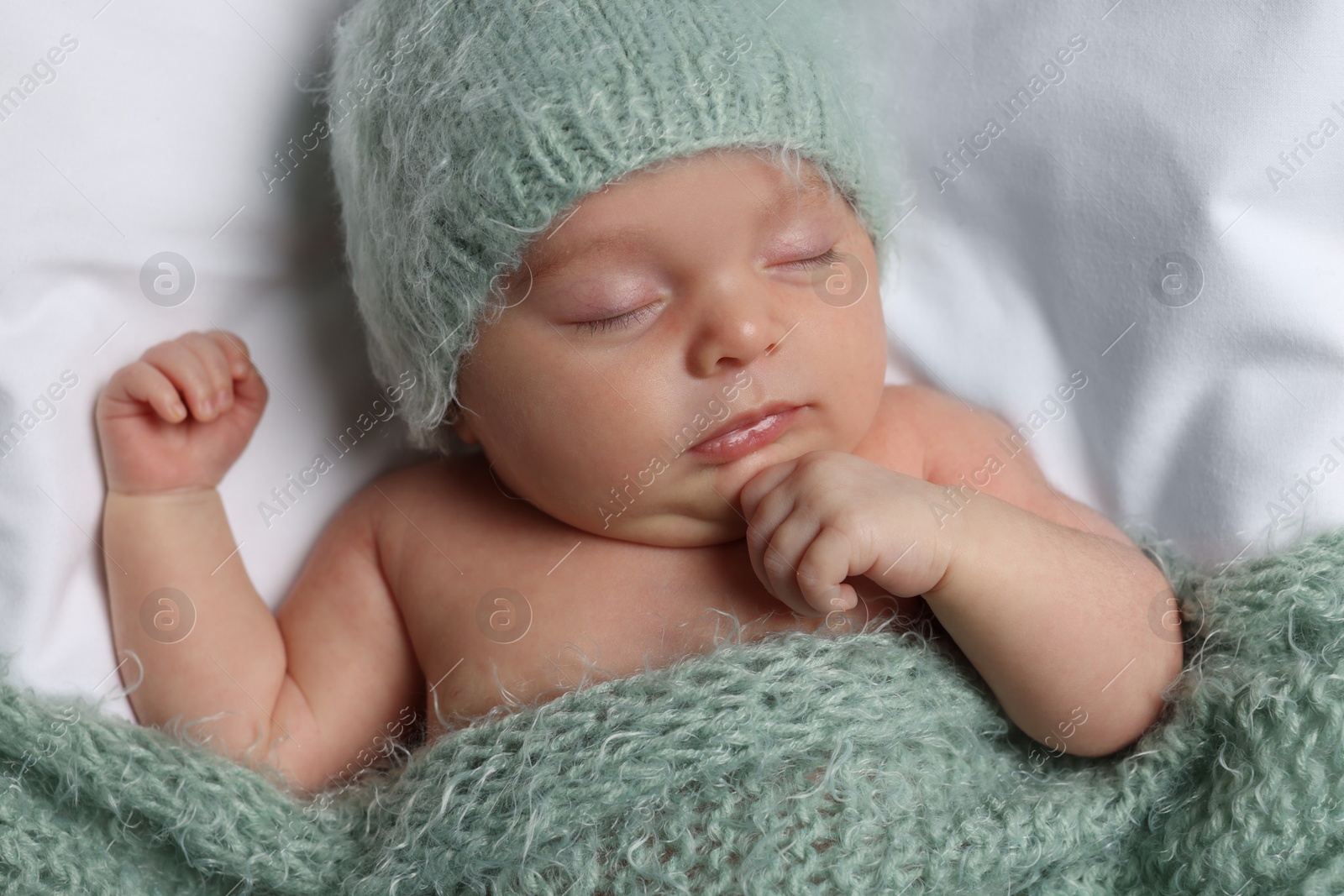 Photo of Cute little baby sleeping under knitted plaid in bed, top view