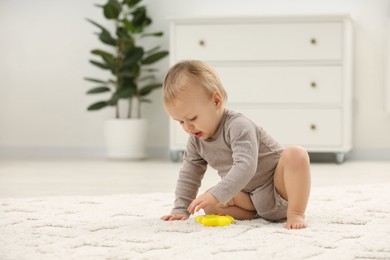 Photo of Children toys. Cute little boy playing with colorful toy on rug at home, space for text