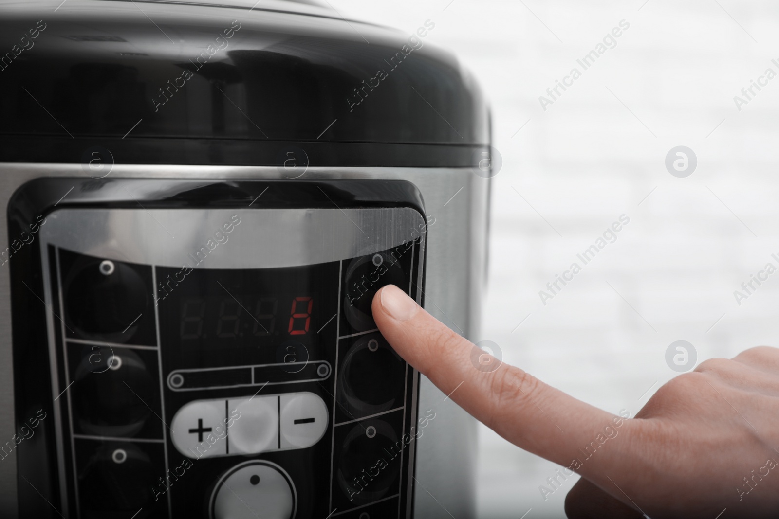 Photo of Woman turning on modern electric multi cooker, closeup