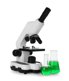 Laboratory glassware with green liquid and microscope isolated on white