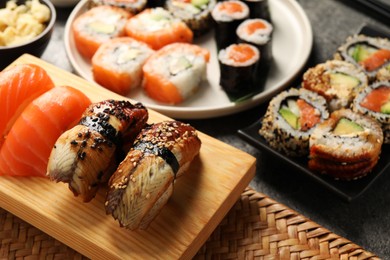 Photo of Different tasty sushi rolls on dark grey table