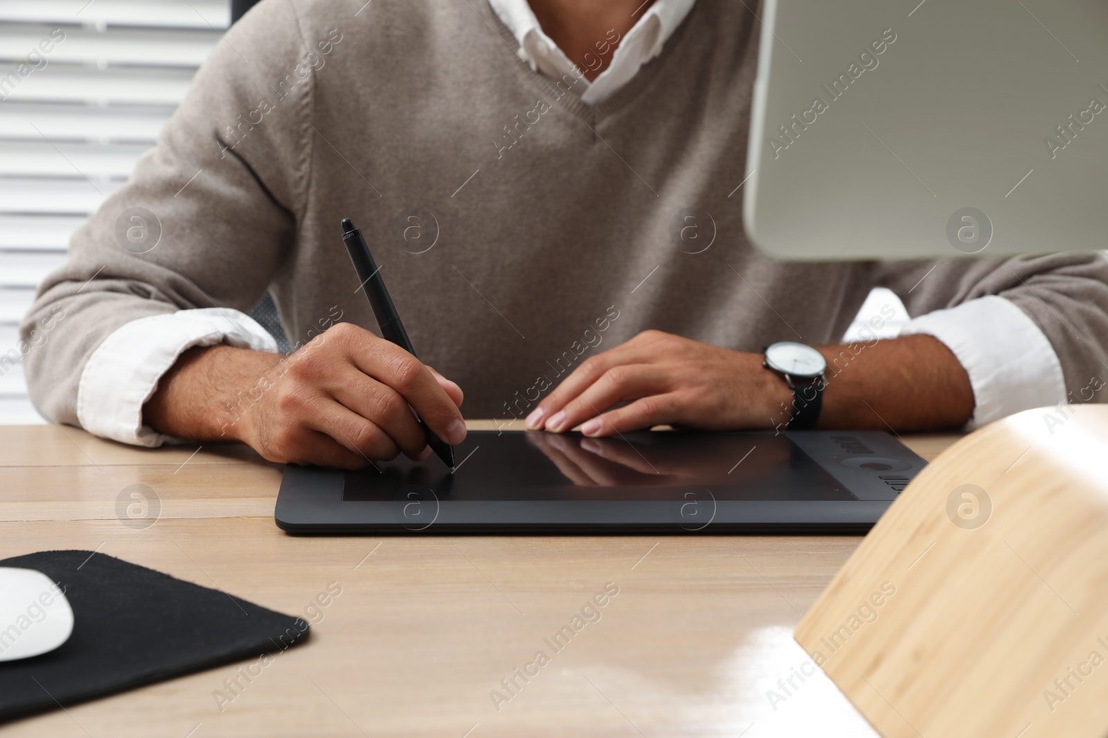 Photo of Professional retoucher working on graphic tablet at desk, closeup