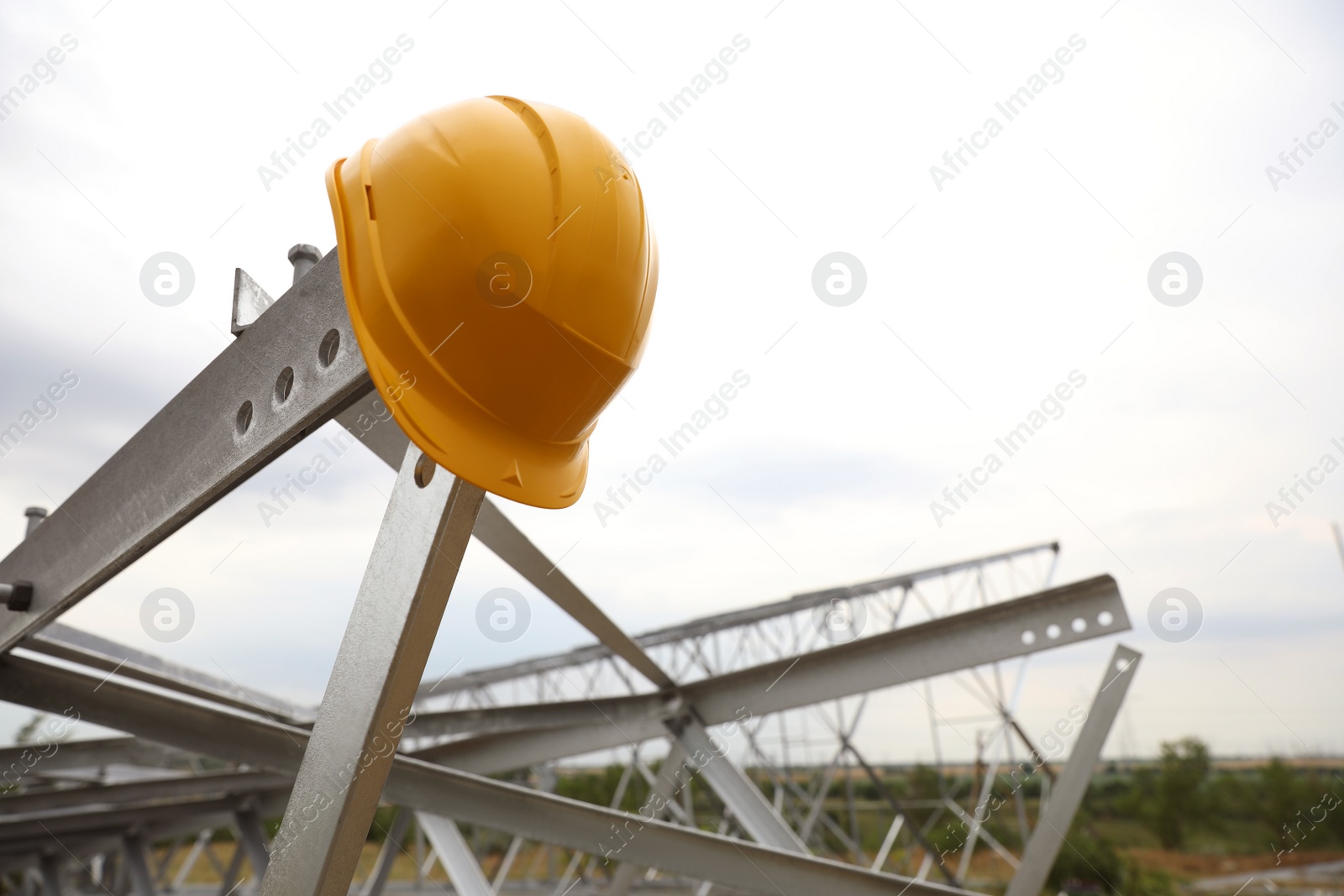 Photo of High voltage tower construction with yellow hard hat outdoors. Installation of electrical substation