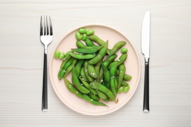 Photo of Green edamame beans in pods served on white wooden table, flat lay