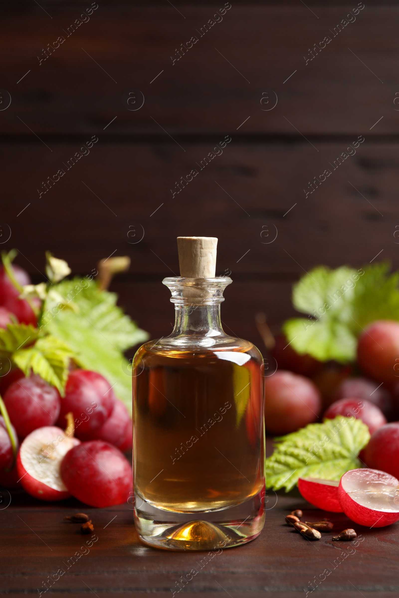 Photo of Bottle of natural grape seed oil on wooden table. Organic cosmetic