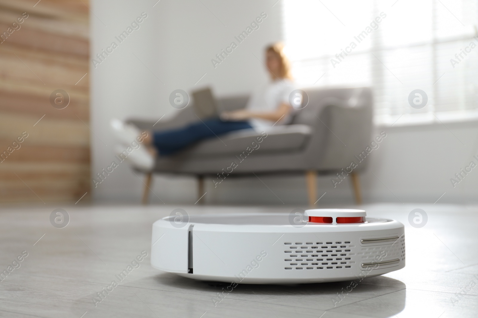 Photo of Woman resting while robotic vacuum cleaner doing her work at home