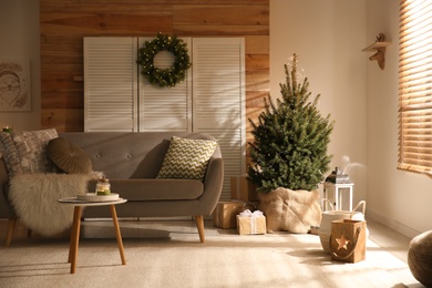 Photo of Spacious room interior with small Christmas tree and wreath