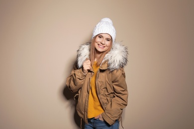 Young woman wearing warm clothes on color background. Ready for winter vacation